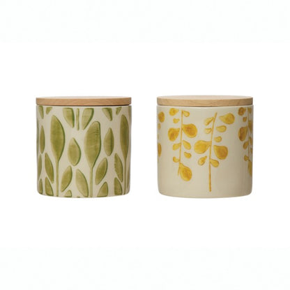 two hand stamped stoneware jars with bamboo lids on a white background