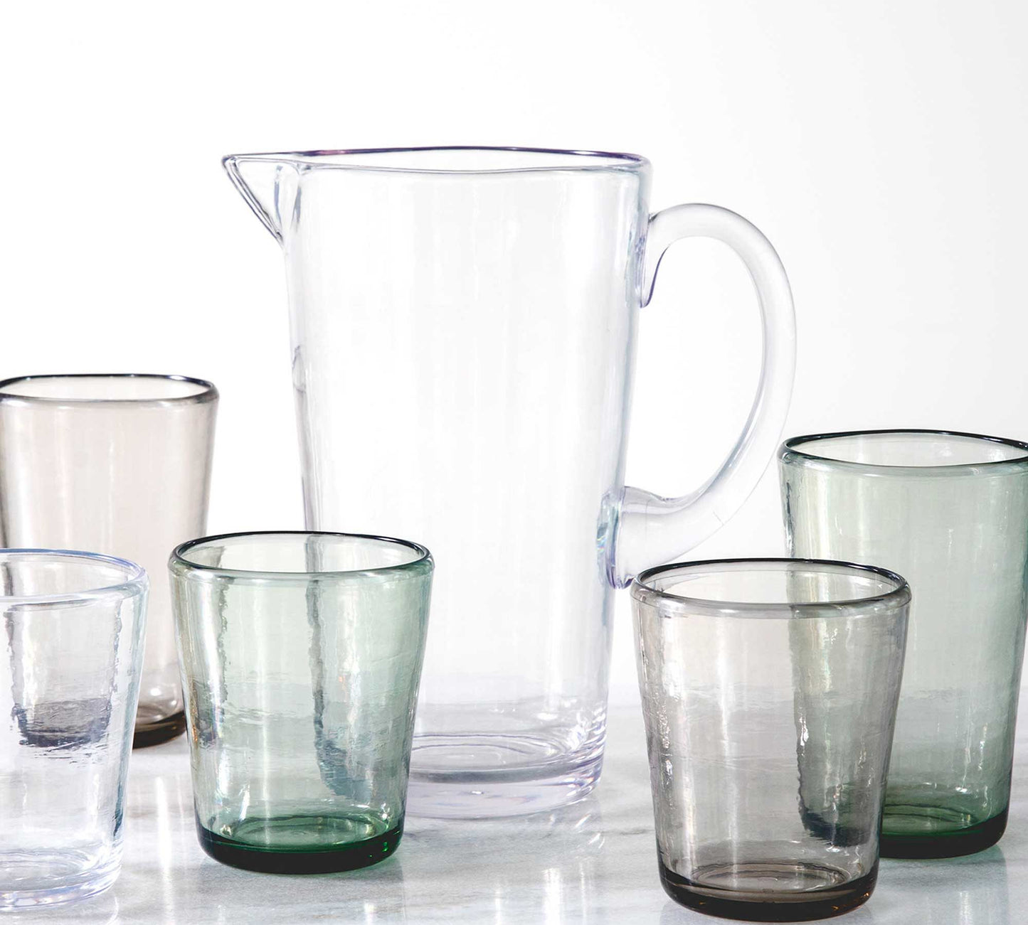 assorted glasses and a clear pitcher on a table.