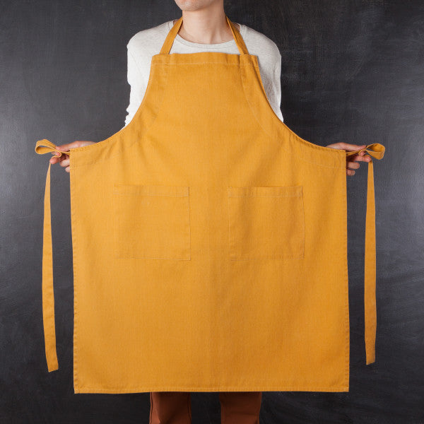 person wearing apron and holding ties out to the side.