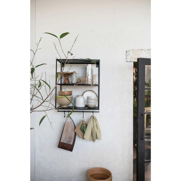 mango wood cutting board with handle hanging from a shelf with decor and dishes on a white wall along with decor greenery