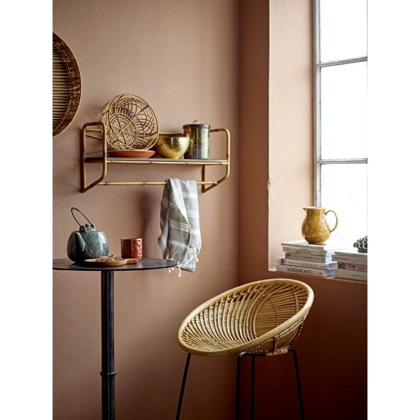 hammered metal bowl on a shelf in a living space next to a window with small table and chair