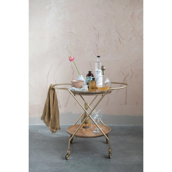 glass decanter with mango wood stopper displayed on a bar cart with wine glasses and a bottle of wine against a tan textured wall