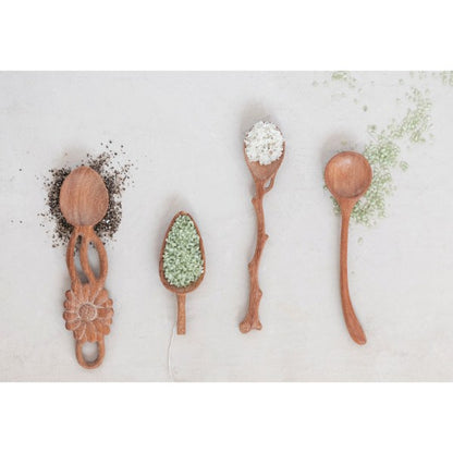 four different hand carved doussie wood utensils filled with spices on a white background