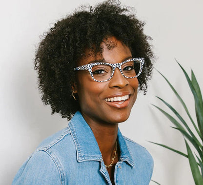 front view of a woman modeling the white and leopard orchid island glasses against a gray background 