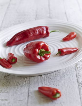 platter on wood table with red bell peppers and chili peppers on it.