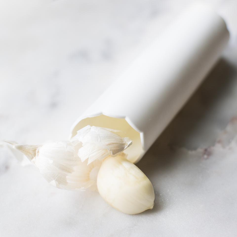 garlic peeler with garlic on marble countertop.