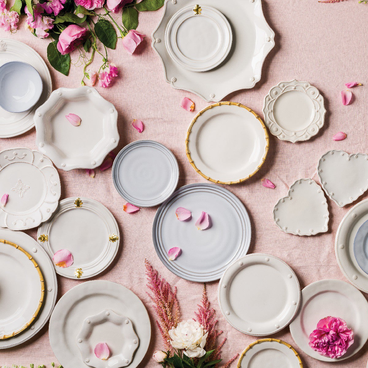 display of plates and bowls on a pink table cloth with flowers and petals