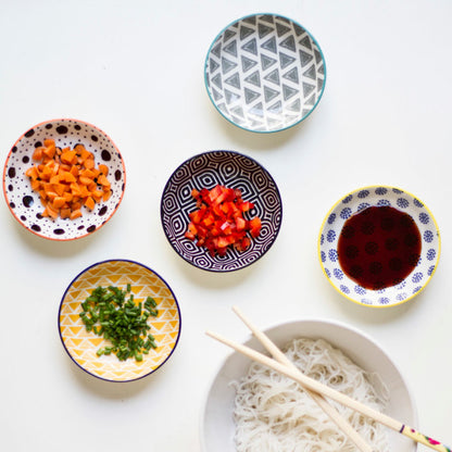 top view of small dishes with assorted patterns filled with chopped veggies or sauce.