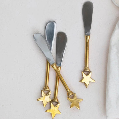 4 stainless steel spreaders with brass handles with a star on the end.