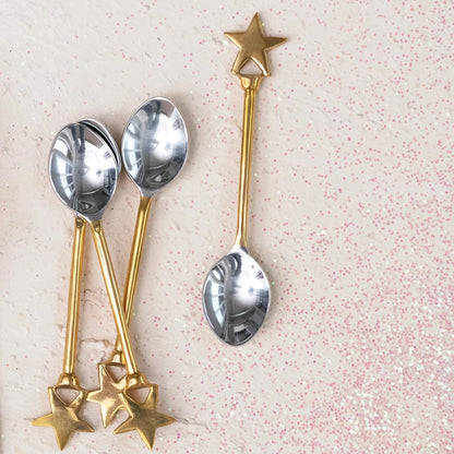 4 stainless steel spoons with brass handles with a star on the end.