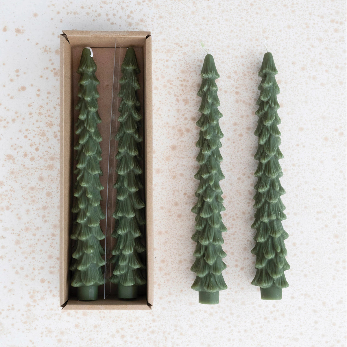 tall dark green tree shaped candles arranged on a gold speckled background.