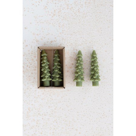 green tree shaped taper candles in the box with 2 other candles laying next to it on a gold speckled background.