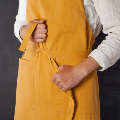 person wearing apron and tying it around their waist.