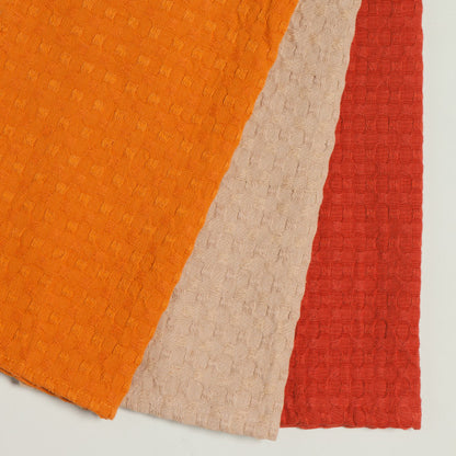 3 waffle weave dish cloths, one each of orange, taupe, and red.