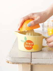 hands holding juice and half an orange.