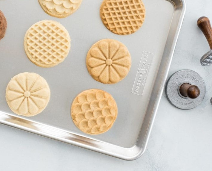 top view of baking sheet with stamped cookies on it and cookie stamps next to it.